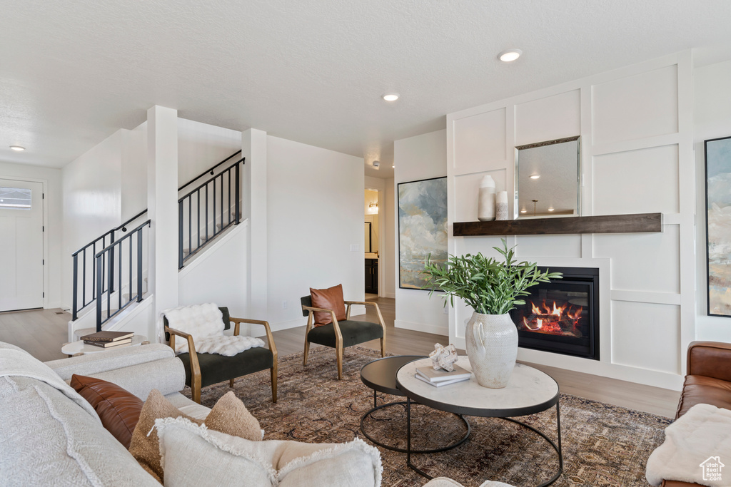 Living area with a glass covered fireplace, stairway, light wood-style floors, and recessed lighting