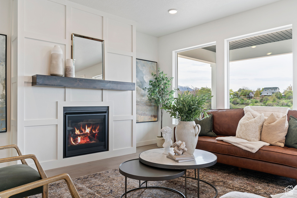 Living room featuring a glass covered fireplace, plenty of natural light, recessed lighting, and wood finished floors