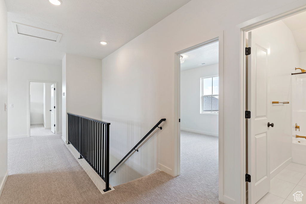 Hall featuring baseboards, light colored carpet, attic access, and an upstairs landing