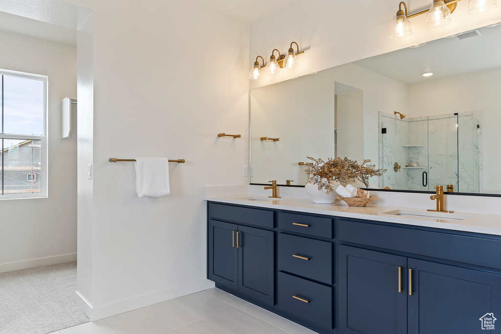 Bathroom featuring a sink, a marble finish shower, baseboards, and double vanity