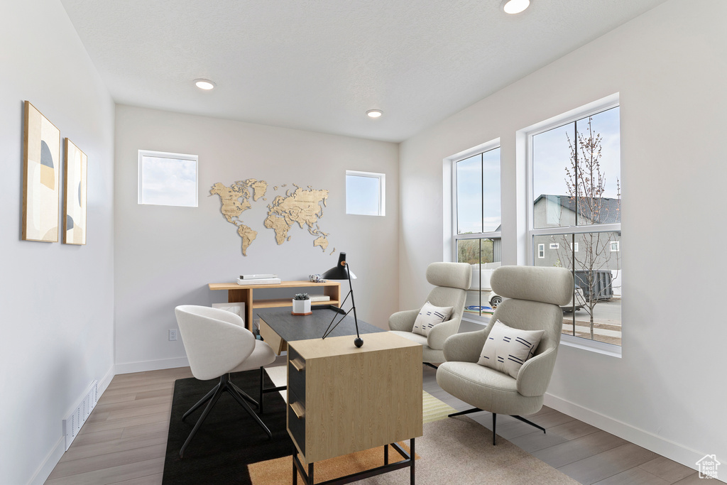 Office area featuring visible vents, baseboards, and wood finished floors