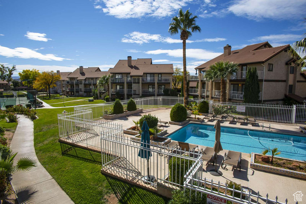 Community pool with a patio, fence, and a residential view