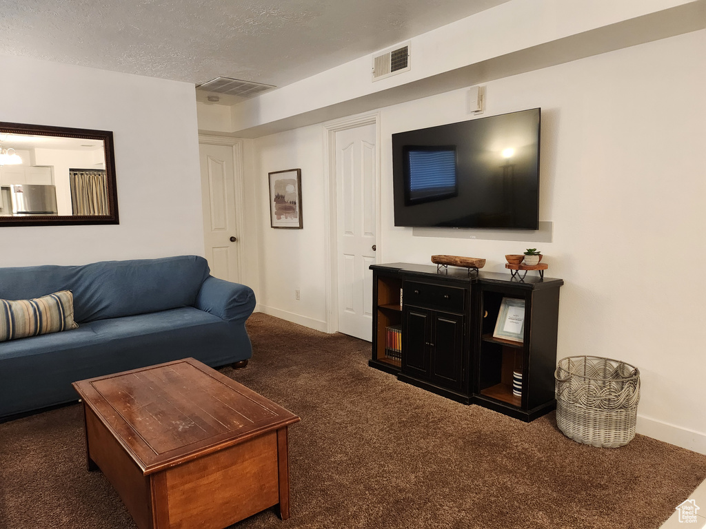 Living room featuring visible vents, carpet, baseboards, and a textured ceiling