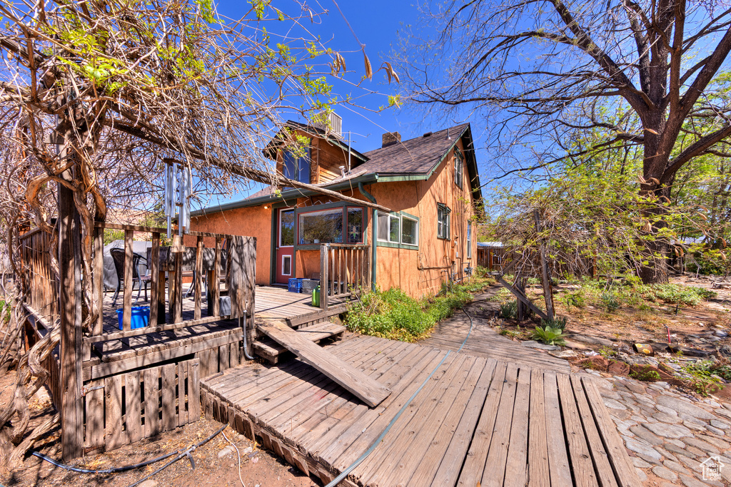 Rear view of property with a chimney, a deck, and roof with shingles