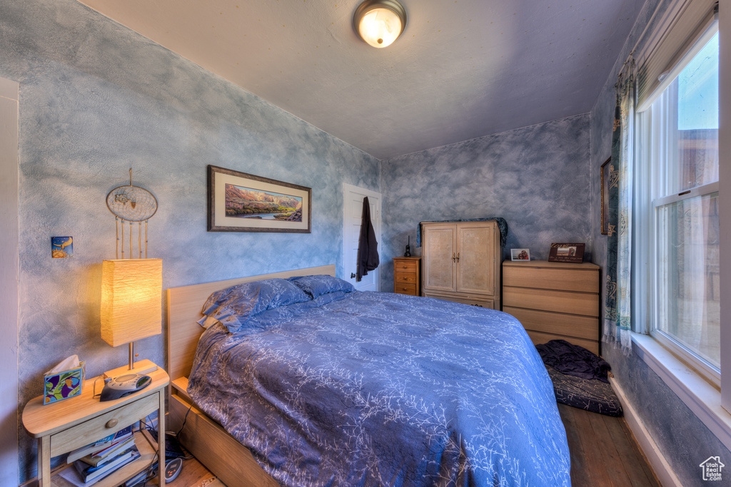 Bedroom with wood finished floors and multiple windows