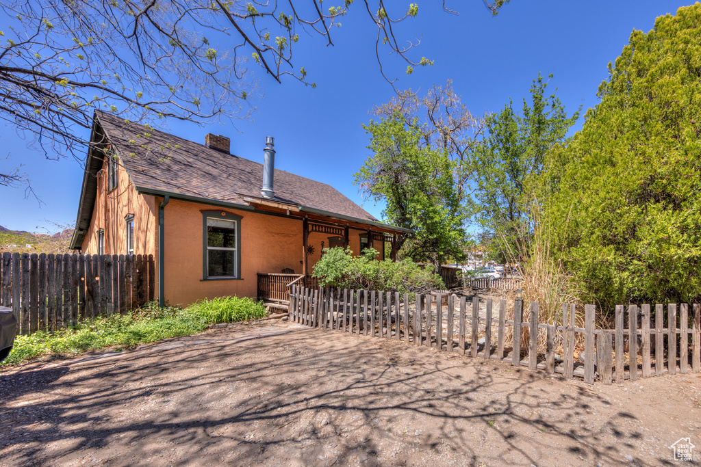 View of front of home with a chimney and a shingled roof