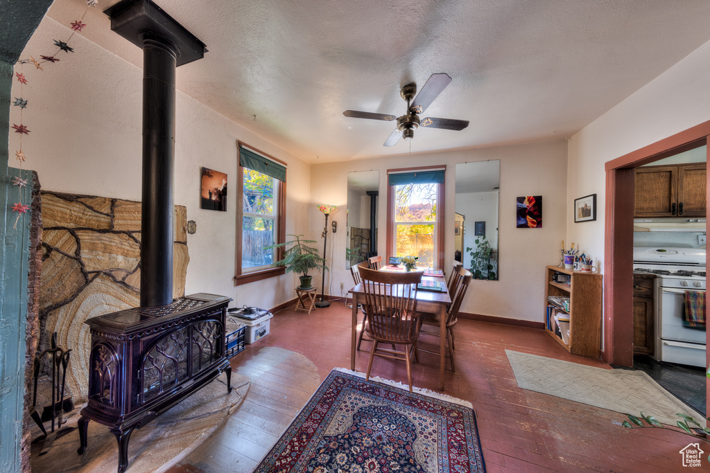 Dining area with hardwood / wood-style floors, a ceiling fan, baseboards, and a wood stove