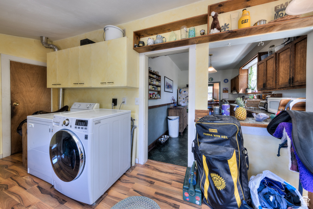 Laundry area with washer and dryer, cabinet space, and light wood finished floors