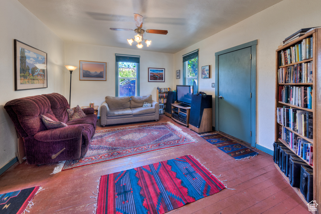 Living area with ceiling fan, wood-type flooring, and baseboards