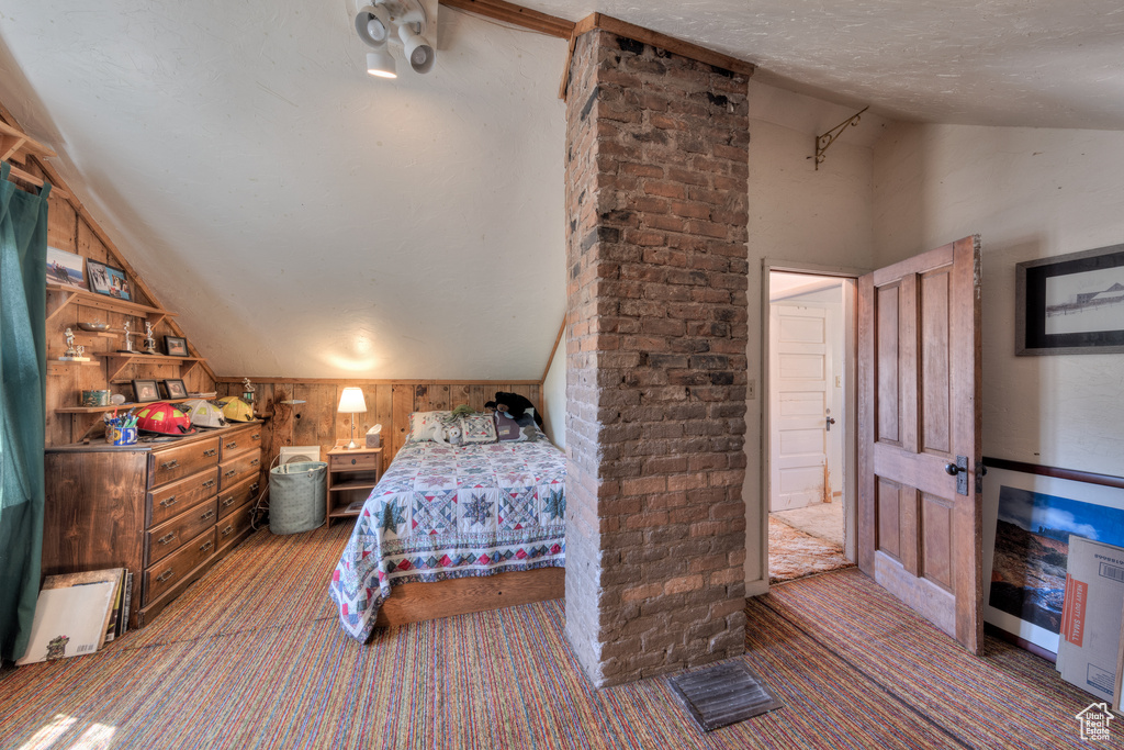 Bedroom featuring lofted ceiling, carpet floors, a textured ceiling, and wood walls