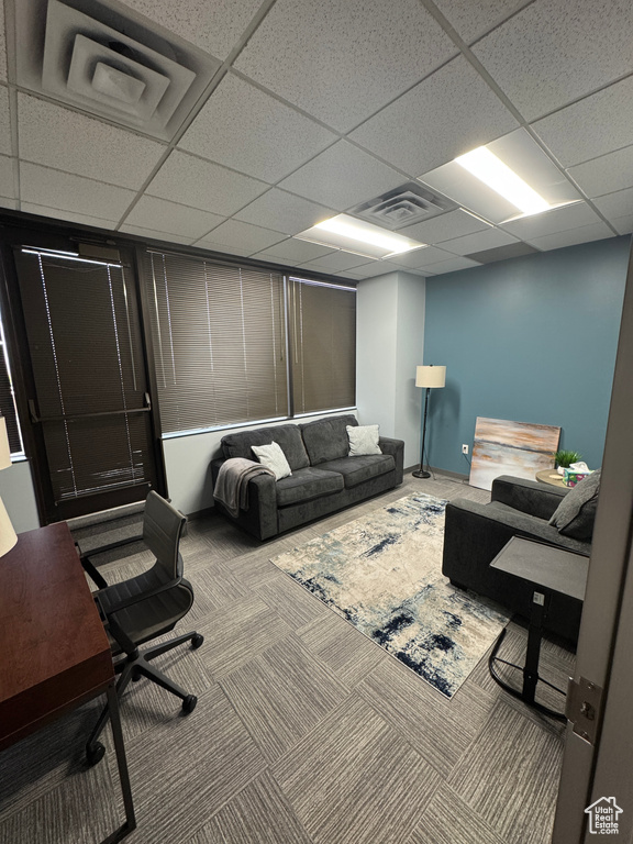 Carpeted living room with visible vents and a drop ceiling