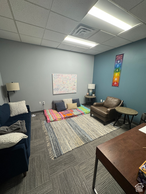 Living room with visible vents, a drop ceiling, and carpet