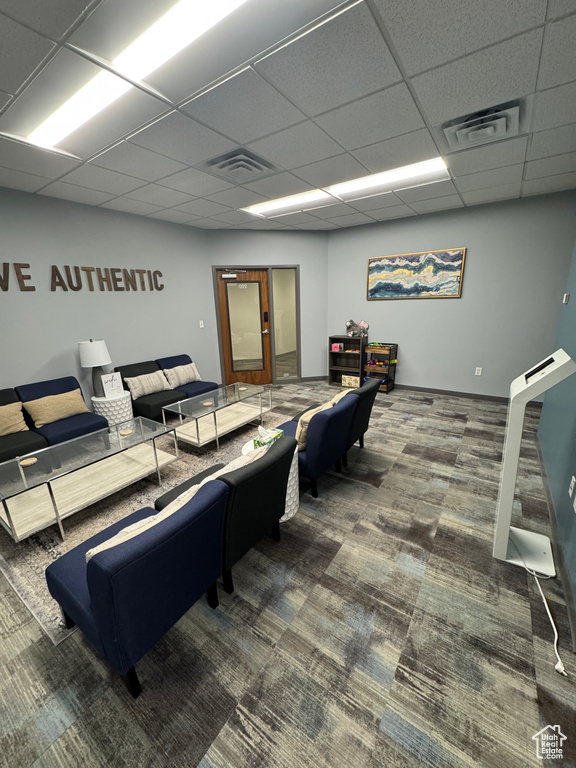 Living area featuring carpet flooring, visible vents, and a drop ceiling