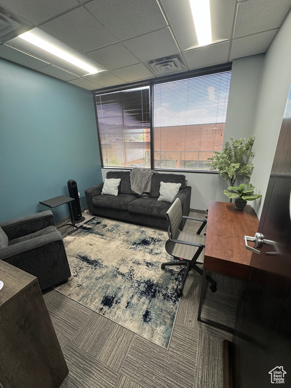 Living area featuring visible vents, baseboards, and a drop ceiling