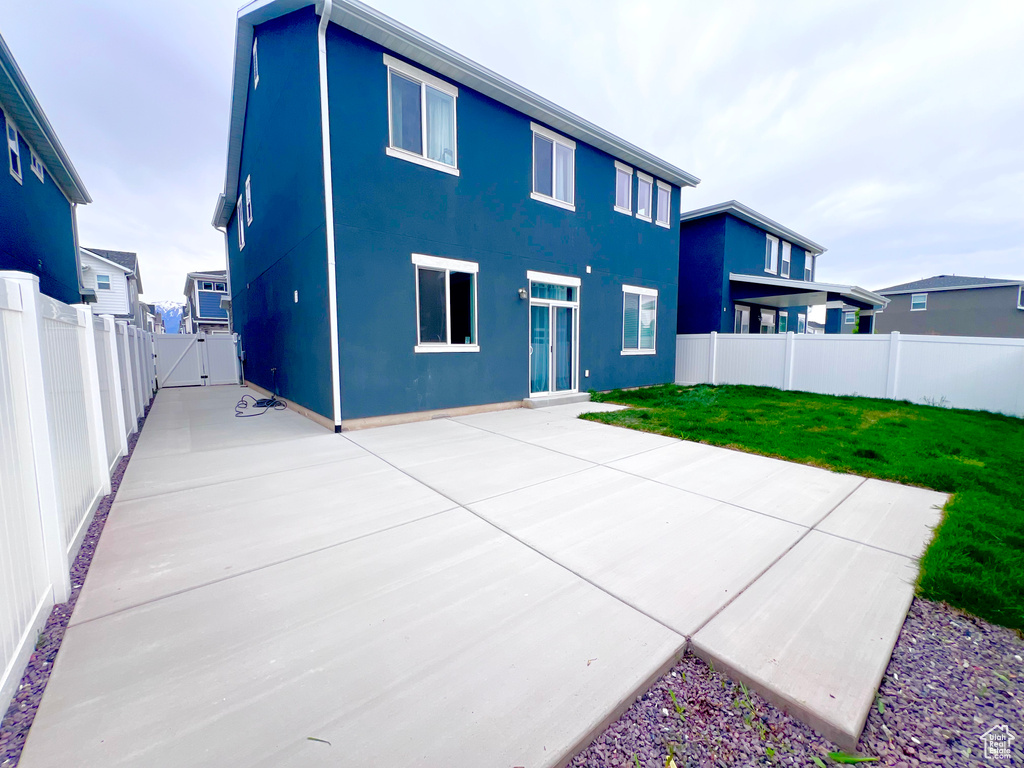 Back of property featuring a lawn, a gate, a fenced backyard, a patio, and stucco siding
