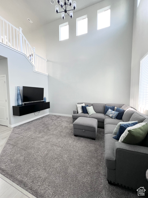 Living room with an inviting chandelier, carpet flooring, a towering ceiling, and visible vents
