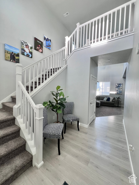 Staircase with baseboards, a towering ceiling, wood finished floors, and visible vents
