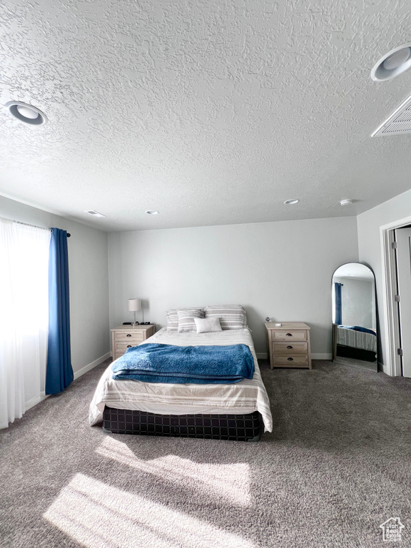 Carpeted bedroom featuring baseboards and a textured ceiling