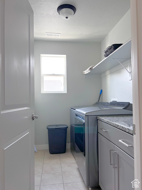 Laundry room with visible vents, light tile patterned flooring, a textured ceiling, cabinet space, and independent washer and dryer