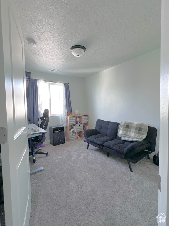 Carpeted home office featuring a textured ceiling and visible vents