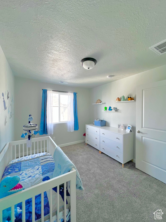 Bedroom featuring visible vents, a textured ceiling, and carpet