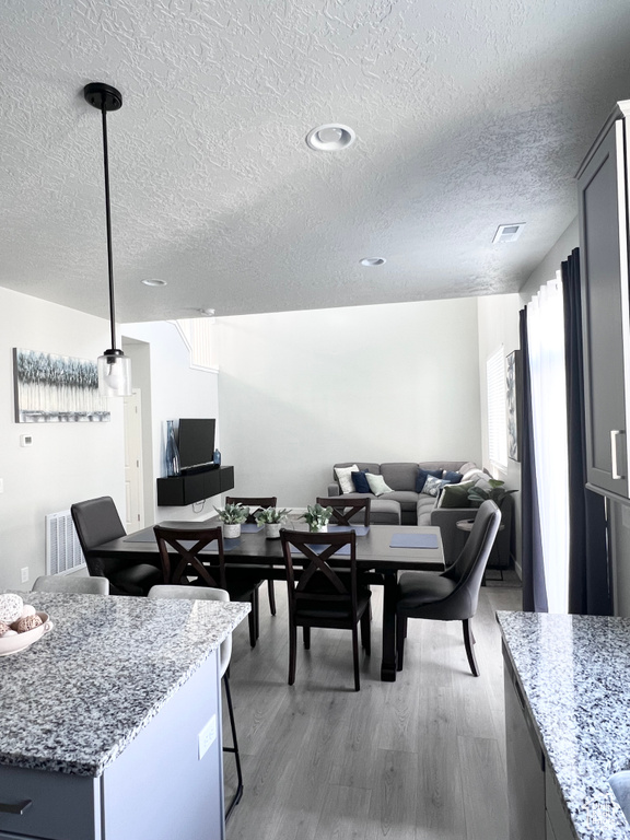Dining space featuring visible vents, a textured ceiling, and wood finished floors