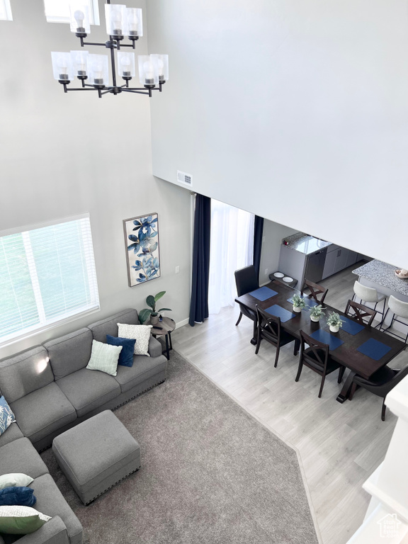 Living area featuring a chandelier, wood finished floors, visible vents, and a towering ceiling