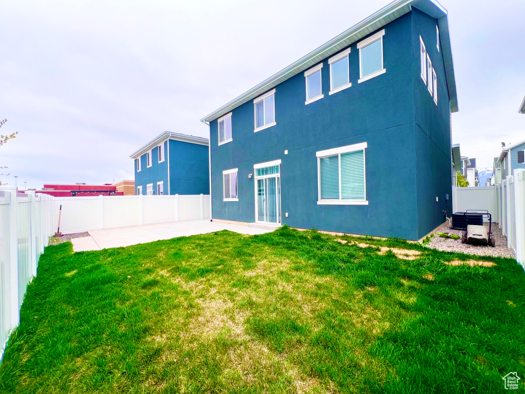 Rear view of house featuring a yard, a patio, a fenced backyard, and stucco siding