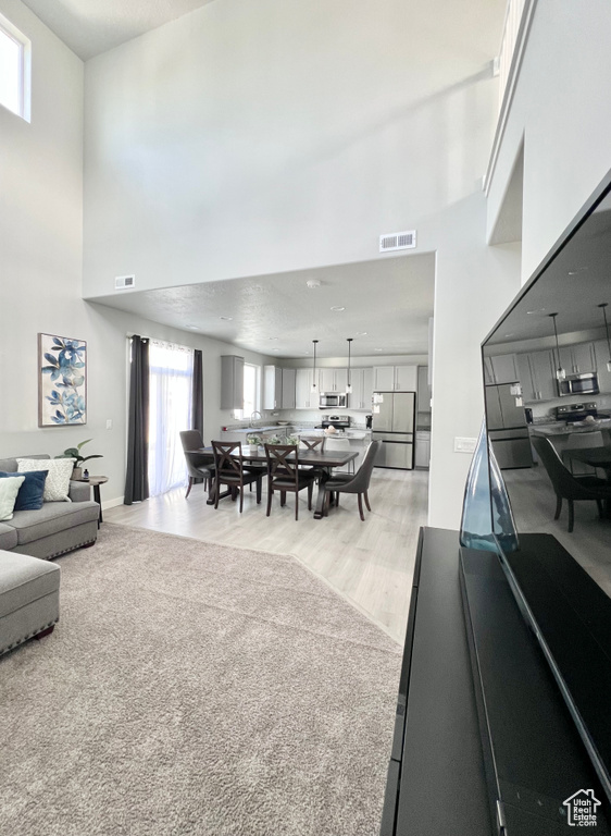 Living room with a high ceiling, visible vents, and light wood-type flooring
