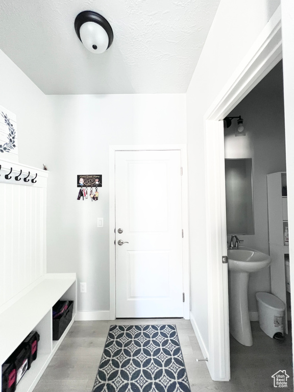 Mudroom with baseboards, a textured ceiling, and light wood-style flooring