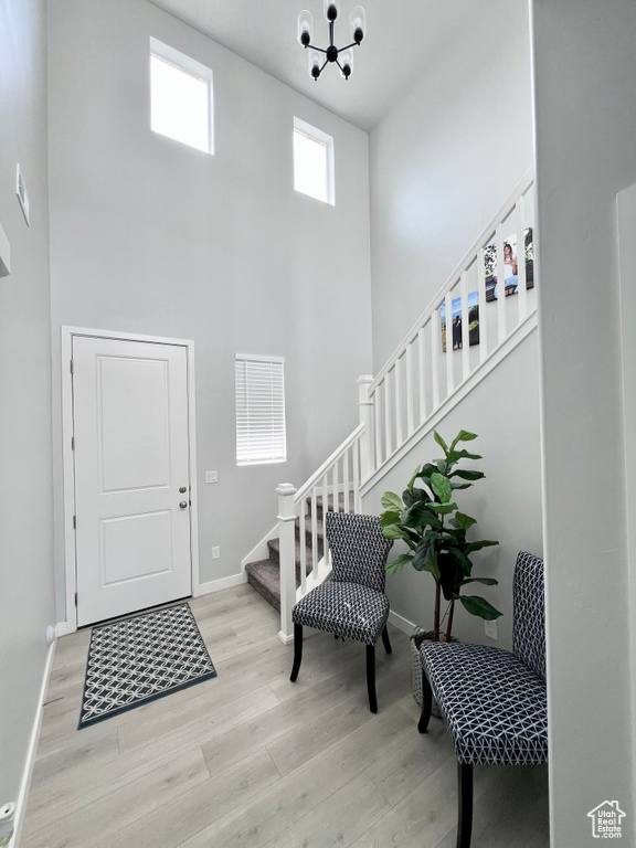 Foyer with a high ceiling, a notable chandelier, stairs, baseboards, and wood finished floors