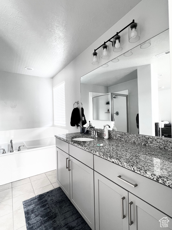 Bathroom featuring vanity, a textured ceiling, a bath, tile patterned floors, and a stall shower