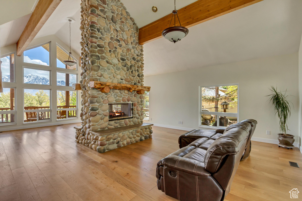 Living room featuring baseboards, beam ceiling, high vaulted ceiling, and a fireplace