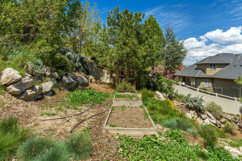 View of yard featuring fence and a vegetable garden