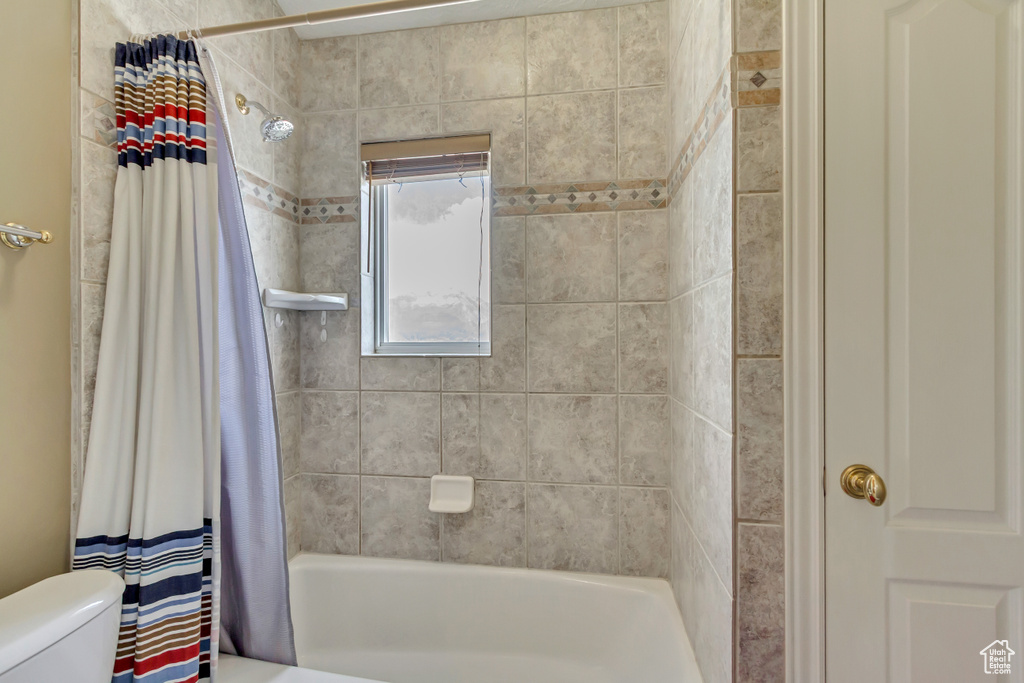 Bathroom with shower / bathtub combination with curtain and toilet