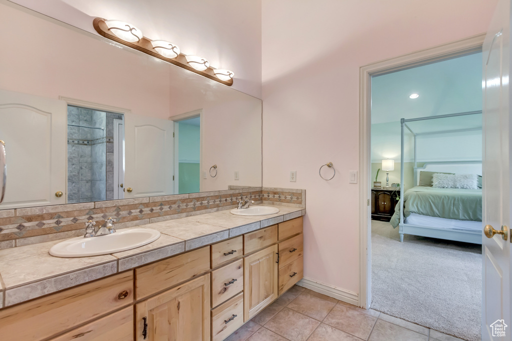 Ensuite bathroom featuring a sink, tile patterned flooring, ensuite bathroom, and double vanity