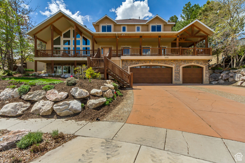 View of front facade with stairway, a garage, driveway, and stucco siding