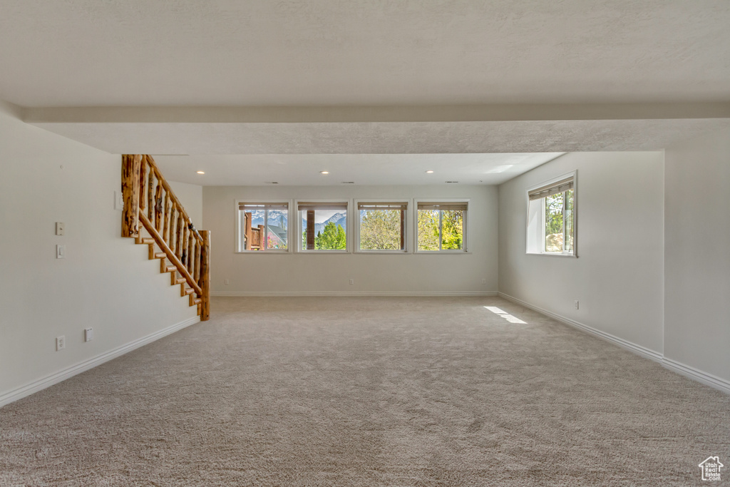 Unfurnished living room featuring recessed lighting, baseboards, carpet flooring, and stairs