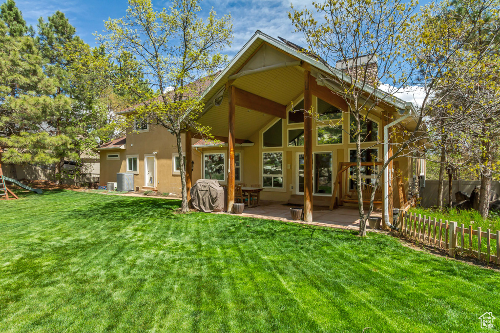 Rear view of house featuring a yard, cooling unit, a fenced backyard, and stucco siding
