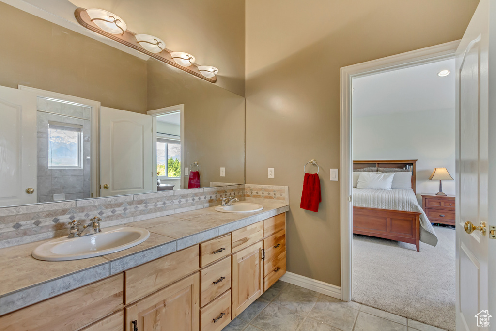 Full bath featuring baseboards, double vanity, tile patterned floors, and a sink