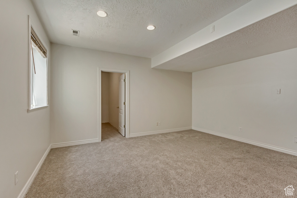 Spare room featuring light colored carpet, a textured ceiling, recessed lighting, baseboards, and visible vents