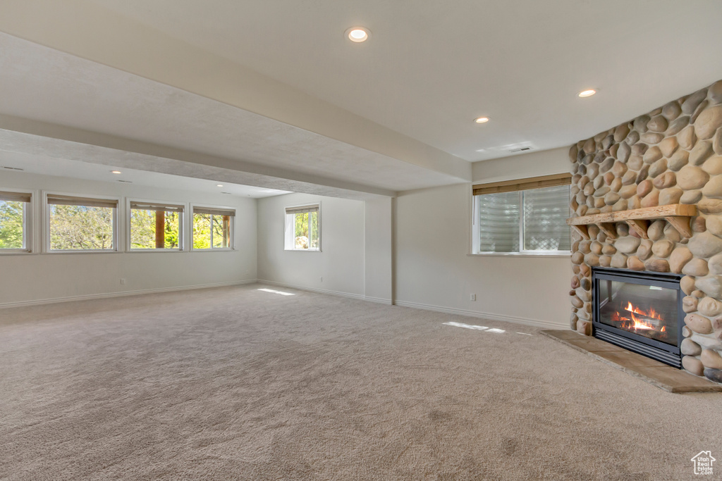 Unfurnished living room featuring carpet floors, recessed lighting, baseboards, and a stone fireplace