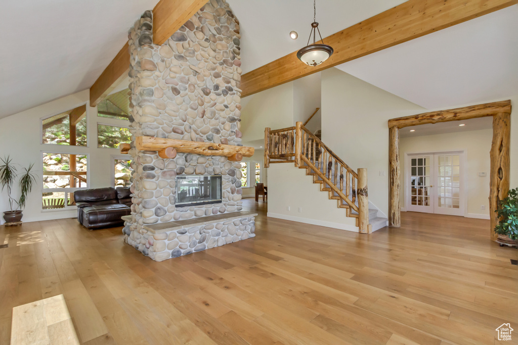 Living area featuring high vaulted ceiling, a stone fireplace, beam ceiling, and hardwood / wood-style floors