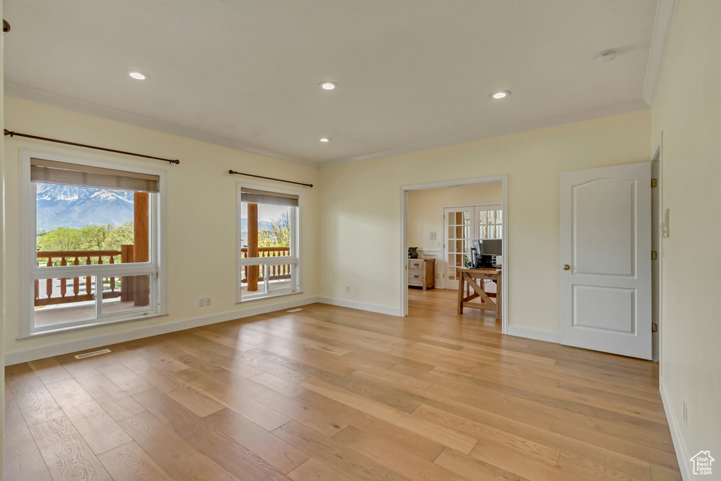 Spare room featuring light wood-type flooring, recessed lighting, baseboards, and crown molding