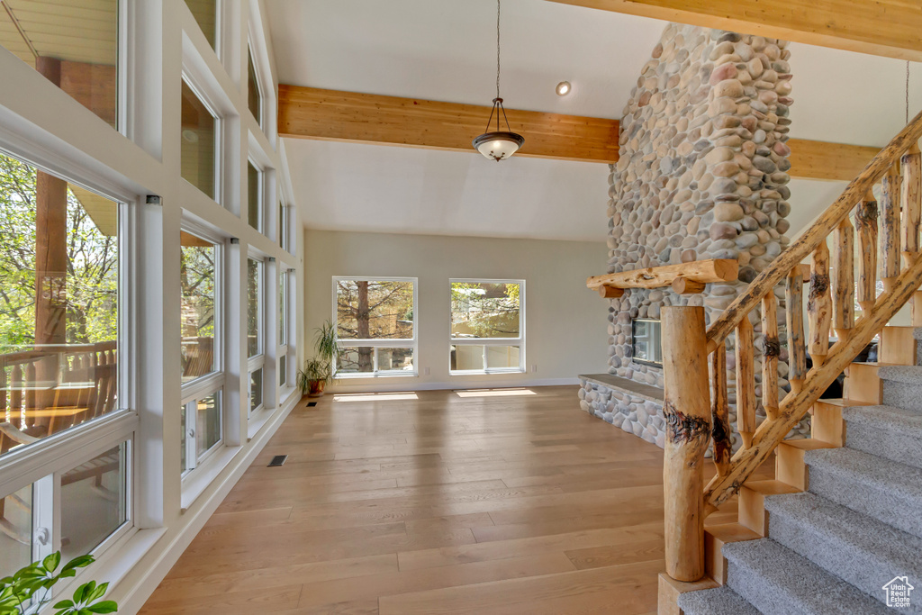 Foyer entrance featuring lofted ceiling with beams, wood-type flooring, a stone fireplace, stairs, and recessed lighting