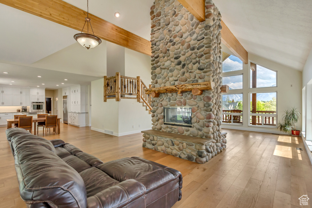 Living room with baseboards, beamed ceiling, light wood finished floors, and high vaulted ceiling