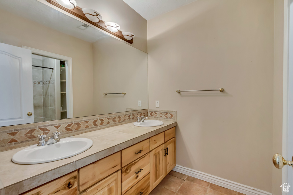 Bathroom featuring a sink, baseboards, tile patterned flooring, and double vanity