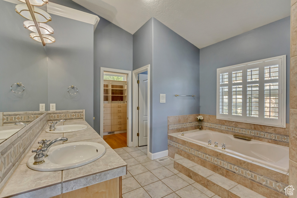 Full bathroom with double vanity, tile patterned floors, a sink, and a bath