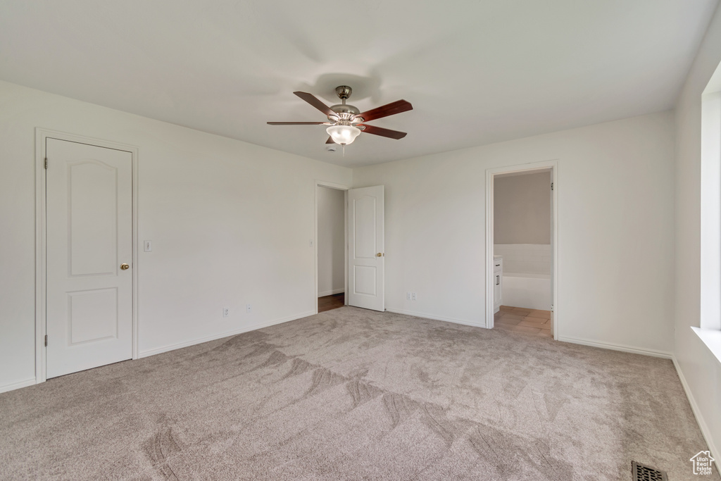Unfurnished bedroom with visible vents, a ceiling fan, baseboards, ensuite bathroom, and carpet flooring