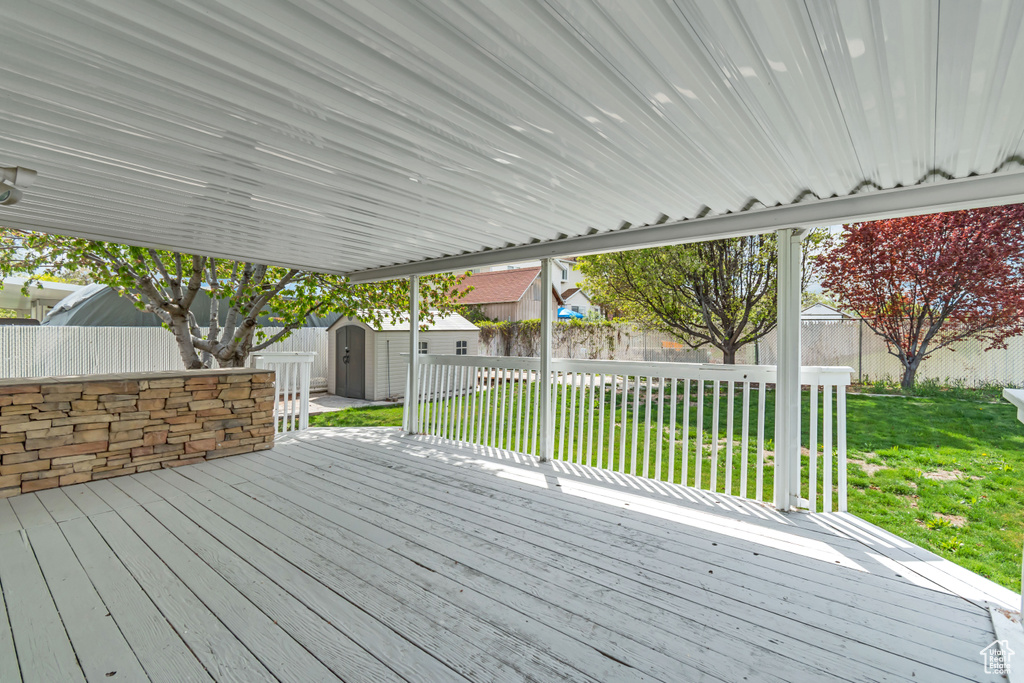 Wooden deck with an outdoor structure, a fenced backyard, a lawn, and a shed